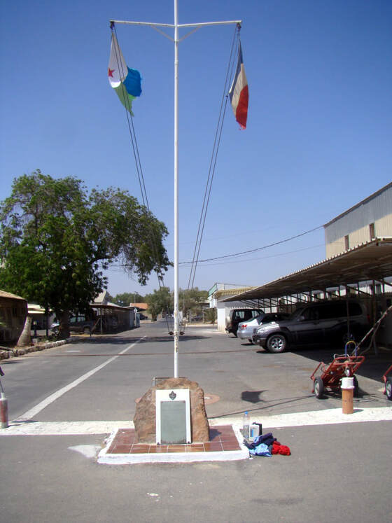 Le mât avec les couleurs djiboutiennes et françaises ; au pied, la stèle du DETALAT de Djibouti. Alat.fr
